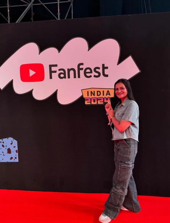 Dimple Malhan, an Indian YouTuber, smiling while recording a vlog for her YouTube channel, "Dimple Malhan Vlogs." She is known for sharing traditional Indian recipes, day-to-day family moments, and homemaking tips, building a loyal fanbase with her relatable and engaging content.
