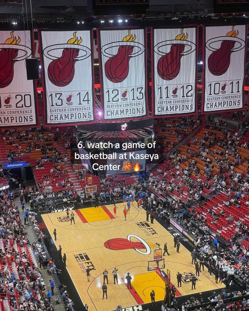 The interior of the Kaseya Center, featuring championship banners and a packed crowd during a Miami Heat basketball game.