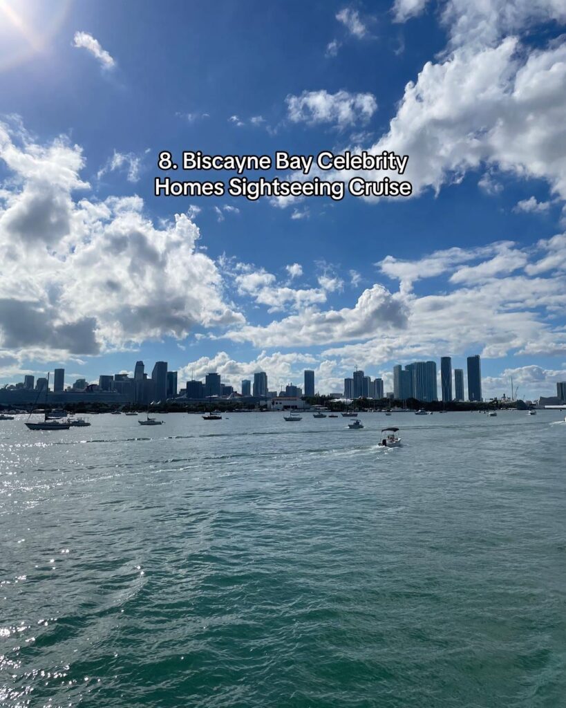 A scenic view of Biscayne Bay with luxury homes, yachts, and the Miami skyline in the background.