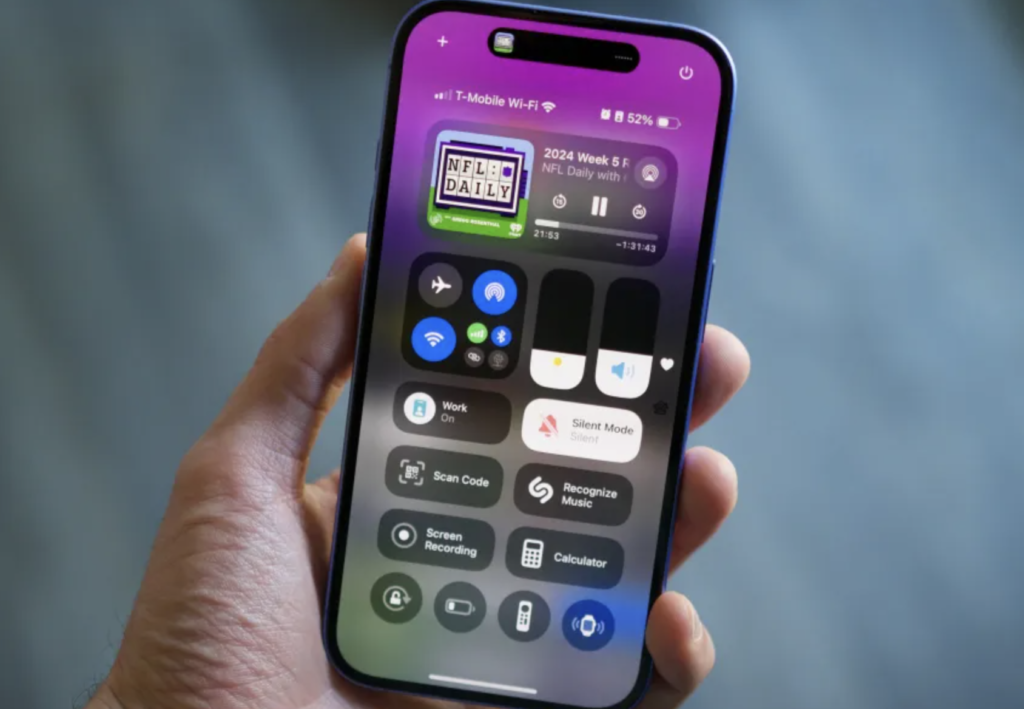 A sleek iPhone 16 lying on a wooden table with its vibrant display on